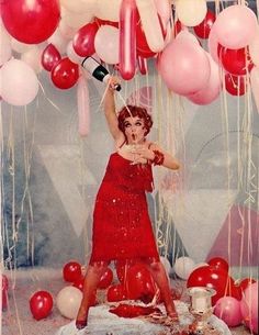 a woman in a red dress is surrounded by balloons