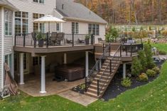 a large white house with a deck and stairs leading to the upper level patio area