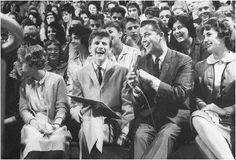 a group of people sitting next to each other in front of a crowd with microphones