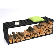 a table made out of logs with a green pillow on it's back end