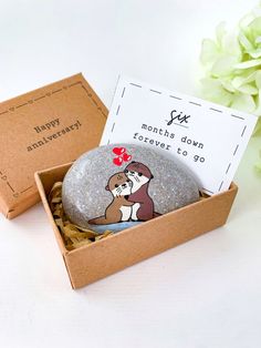 a rock with a dog on it sitting in a box next to a card that says happy anniversary