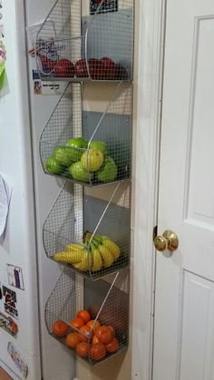 a metal shelf filled with lots of fruit on top of a white refrigerator freezer