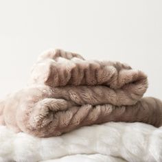 two blankets stacked on top of each other in front of a white wall and floor