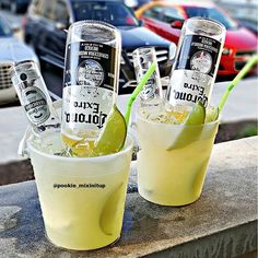 two glasses filled with drinks sitting on top of a cement wall next to each other