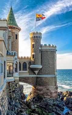 a castle on the shore with a flag flying above it