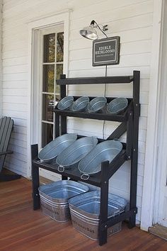 an outdoor kitchen with pots and pans on the outside wall, next to a porch