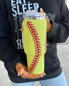 a woman holding a yellow and red baseball tumbler cup with the word eat sleep team on it