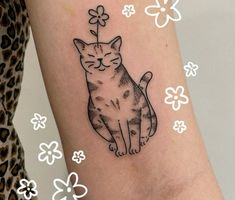 a cat tattoo on the arm with flowers around it