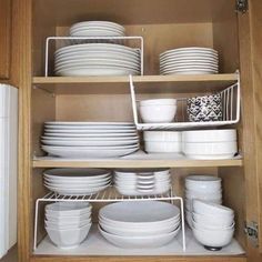 a cabinet filled with white dishes and plates