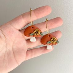 a hand is holding two small earrings with flowers on them