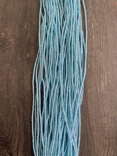 several strands of light blue seed beads on a wooden surface, with one bead in the middle