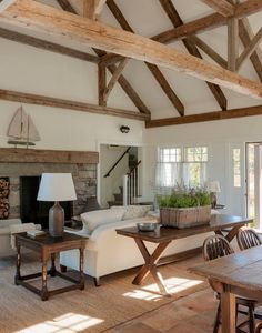 a living room filled with furniture and a fire place under a wooden beamed ceiling