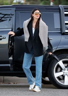 a woman is standing in front of a black suv with her hand on the door handle