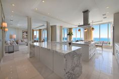 a large kitchen with marble counter tops and an island in front of the window overlooking the ocean