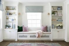 a window seat in a white room with built - in bookshelves and shelves