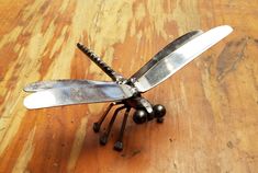 a metal dragonfly sitting on top of a wooden table