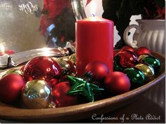 a red candle sitting on top of a wooden bowl filled with ornaments