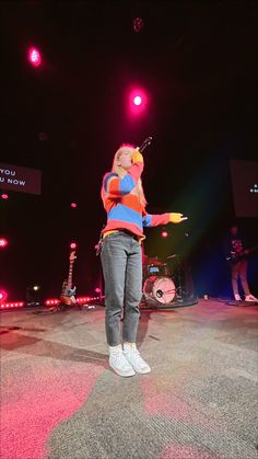 a woman standing on top of a stage holding a yellow object in her right hand