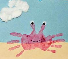 a child's handprinted picture of a crab on the beach with clouds in the background