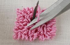 two pairs of scissors are on top of a crochet flower with pink yarn