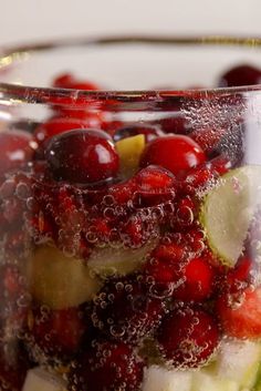 a glass filled with fruit and water on top of a table