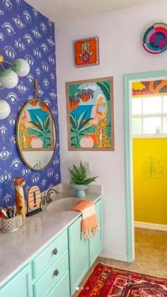 a bathroom with blue wallpaper and colorful artwork on the walls