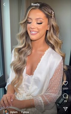 a woman with long blonde hair wearing a white blouse and pearls on her head is looking at the camera