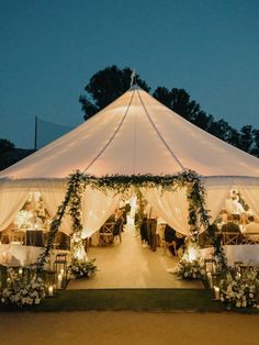 a large tent with tables and chairs set up for an outdoor wedding reception at night