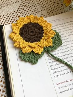 a crocheted sunflower on top of an open book