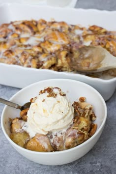 a white bowl filled with dessert next to a serving dish full of ice cream and cinnamon rolls