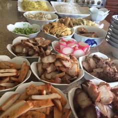 bowls filled with meat and vegetables sitting on a counter top next to plates full of food