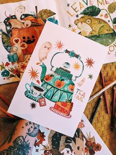 some cards with teapots and cats on them are laying next to crayon markers