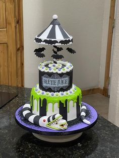 a three tiered cake decorated with black, white and green icing on a table