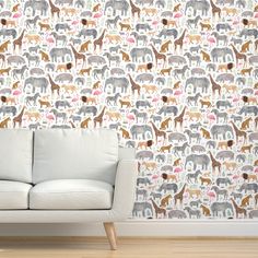 a white couch sitting in front of a wall with animals on it