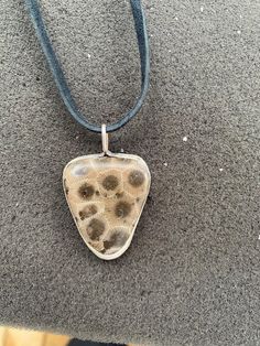 This is a great looking stone with great webbing! This stone was found on a beach in Leland Michigan which makes it a product of Lake Michigan.  This is NOT a 100% silver pendant. The sides and ring are soft silver while the backing is a simple metal  The cord is black colored Leland Michigan, Traverse City Mi, Petoskey Stone, Lake Michigan, Stone Pendant, Stone Pendants, Silver Pendant, Michigan, Jewelry Necklace Pendant