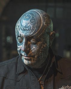 a man with tattoos on his face wearing a black shirt