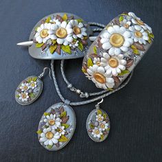 three pieces of jewelry with flowers painted on them