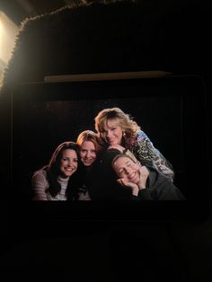 a group of women standing next to each other in front of a light on a wall