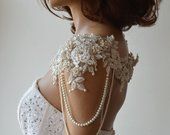 the back of a woman's dress with pearls and lace on her neckline