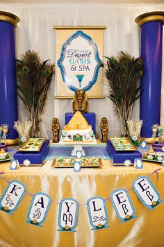 a table topped with lots of food next to tall blue and yellow pillars in front of a white wall