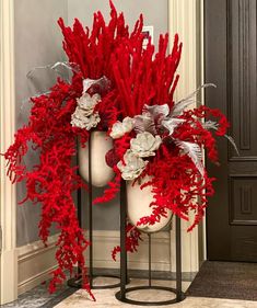 two vases with red and white flowers are on display in front of a door