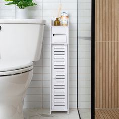 a white toilet sitting next to a wooden stand with a plant on top of it