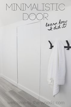 a white towel hanging on the wall next to two black hooks