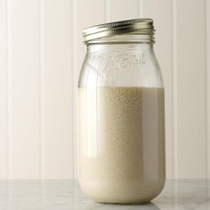 a glass jar filled with liquid sitting on top of a counter next to a white wall