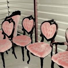 there are many pink chairs with hearts on them in front of a mirror that is leaning against the wall