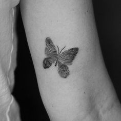 a black and white photo of a butterfly tattoo on the left arm with spirals in it