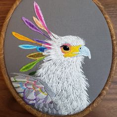 a white bird with multicolored feathers on it's head in a wooden hoop