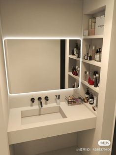 there is a bathroom sink and mirror with lights on the wall above it in front of shelving units