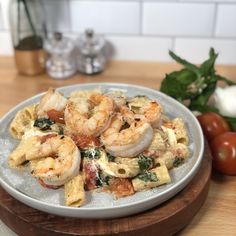 a plate of pasta with shrimp and spinach on the side next to tomatoes, garlic, and basil