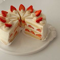 a cake with white frosting and strawberries is cut in half on a plate